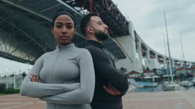 Aktif giyimde güven ve takım çalışması sergileyen ve çeşitli fitness ortaklığı hedeflerini temsil eden iki uygun yetişkinin düşük açılı görüntüsü