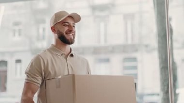 Profesyonel bir kurye, kapalı bir ortamda müşteriye büyük bir karton kutu verir. Takas ve teslimat anını yakalar..