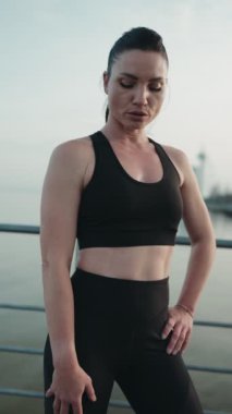 Siyahi aktif giysili kendinden emin genç bir kadın yoğun bir egzersizden sonra poz veriyor, rahat bir tavırla kameraya bakıyor..