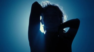 Dans eden tanınmayan bir kadının zarif silueti. Huysuz mavi bir arka ışıkla vurgulanmış. Zarafet ve şehvet kavramı.