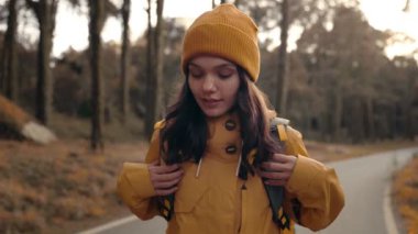 Genç bir kadın yürüyüşçü sakin bir kır yolunda yürüyor, günün sonunda sıcak günbatımını kucaklıyor..