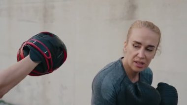 Atletizmde kararlı bir kadın trenleri boks yapar, eldivenleriyle yumruk atar, odaklanır ve güçlenir..