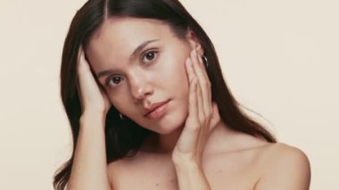 20 'li yaşlarda güzel bir genç kadının portresi, tenine dokunduğunda sakin bir yüz ifadesi, güzelliği ve cilt bakımını simgeliyor..