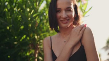 Mutlu, güzel, genç bir kadın kameraya neşeyle gülümsüyor. Kaygısız, neşeli ve yaz güneşinin tadını çıkarıyor..