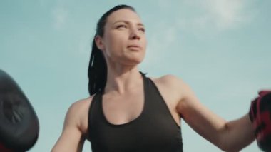 İki kadın boks antrenmanına gidiyor. Biri diğerine yakın plan bir çekimde boks bloknotu tutuyor..