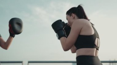 Açık havada boks tekniklerini uygulayan iki aktif kadın açık gökyüzü altında odaklanmış ve kararlı..
