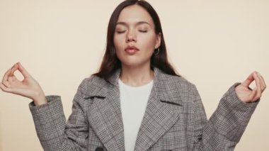 Sakin genç bir kadın şık giysiler içinde, gözleri kapalı meditasyon yapıyor, huzurlu bir ortamda huzuru buluyor..