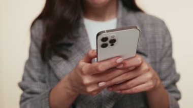 Detaylı bir yakın çekim, vurgu için bulanık arkaplan ile modern bir akıllı telefondan mesaj çeken bir kişinin ellerini yakalar.
