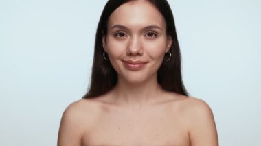 Çıplak omuzlu, gülümseyen genç bir kadının portresi, bir güzellik konseptini tasvir ediyor..