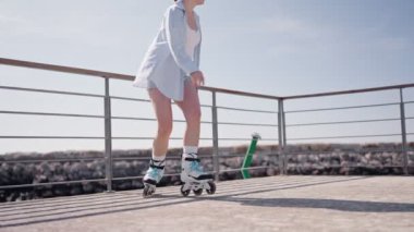 Güneşli bir günde deniz kenarında paten kayan bir kadın. Manzaralı bir ortamda rahatlık ve spor faaliyetlerinin tadını çıkarmak..