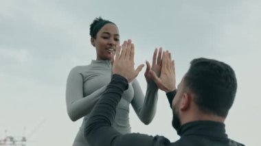 Bir kadın, erkek fitness partnerinin yardımı ile, takım çalışması ve adanmışlık üzerine açık hava karın kasları antrenmanına katılır..