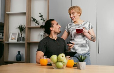Mutlu çift güne sabah çayıyla başlıyor, sohbete girişiyor ve evlerinin mutfağında sosyal medyayı kontrol ediyor..