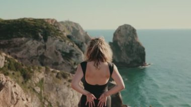 Kolları havada bir kadın, görkemli sahil manzarasını anlamlı ve sanatsal bir şekilde kucaklıyor. Bir an için özgürlük ve doğa ile bağlantı kurmak..