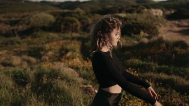 Güzel, güneşli bir alanda sırtını yaslayan, doğa ve sükuneti kucaklayan genç bir kadının yan görüntüsü..