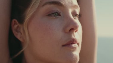 Kaldırılmış elleri olan güzel bir kadının yakın çekimi, doğal özelliklerini ve dingin ifadesini vurguluyor, yumuşak doğal ışığa yakalanıyor..