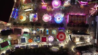 Kalabalık bir eğlence parkının hava görüntüsü ya da gece yarısı insanların gezintilerden, oyunlardan ve eğlencelerden hoşlandığı bir manzara..