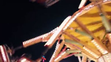 Geceleri lunapark gezintisi. Yanıp sönen ışıklar ve hızlı hareket bir heyecan ve eğlence hissi veriyor..