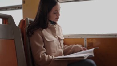 Şehir içi seyahat ve teknoloji kullanımını somutlaştıran metro istasyonunda beklerken akıllı telefonuna odaklanan genç bir kadın.