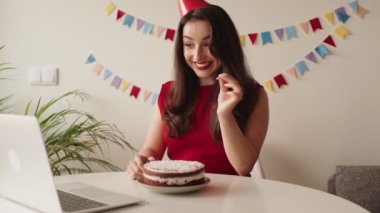 Neşeli bir kadın evde pasta ve mumlarla doğum gününü kutlarken ailesiyle video görüşmesinin keyfini çıkarıyor..