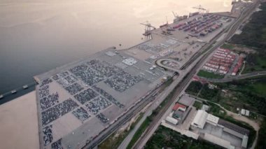 Günbatımında kargo ve konteynırlarla dolu endüstriyel bir limanın hareketli aktivitesini ve karmaşık altyapısını yakalamak için tepeden ateş edildi..