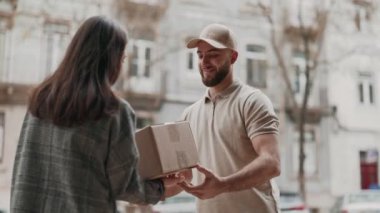 Müşteri kapılarına bir teslimat alıyor, kuryeden bir paket kabul ediyor, modern dağıtım hizmetlerindeki kolaylığı ve kişisel etkileşimi tasvir ediyor..