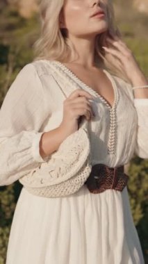 Güneşli bir öğleden sonra doğanın ortasında bohem beyaz elbiseli bir kadının yakın çekimi. Moda, yaşam tarzı ve seyahat markaları için ideal..