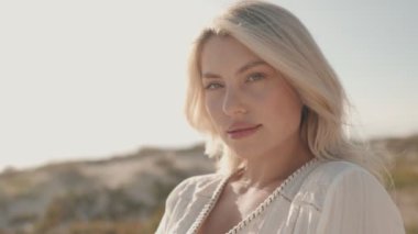 Güzel ve baştan çıkarıcı mavi gözlü sarışın model güneşli bir günde kameraya poz veriyor..