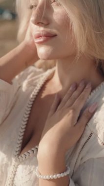 Genç sarışın kadın, güneşin sıcacık parıltısında güneşlenen sessiz bir yansımanın tadını çıkarıyor. Sarışın, hafif ışıklandırmalı, boho tarzı elbiseli ve minimalist estetik bir kadın..