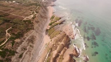 Praia Magoito sahilinin havadan görünüşü, Sintra, Portekiz. Turkuaz su, dalgalar, plaj ve sahil kayalıklarıyla muhteşem bir manzara. Portekiz 'de yaz. İnsansız hava aracı görüntüleri. 4k