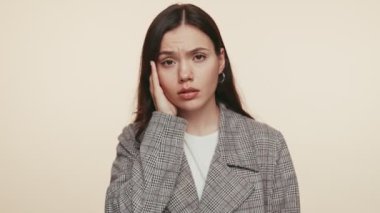 Ekose ceketli genç bir esmer kadın sıkıntılı görünüyor, başını ağrıdan tutuyor, şiddetli bir baş ağrısı ya da migreni gösteriyor..