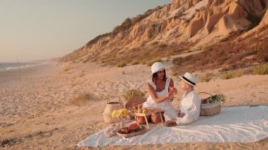 Bir anne ve küçük oğlu güneşli bir plajda rahatlatıcı bir pikniğin tadını çıkarıyorlar, birlikte mutlu anılar yaratıyorlar..