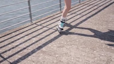 Güneşli bir günde, rıhtımda paten kayan kadın, açık hava fitness ve rahatlığı kucaklıyor..