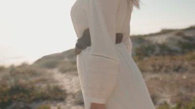 Sahilde yürüyen, dalgalı beyaz elbiseli bir kadının baştan çıkarıcı yavaş çekim çekimi..
