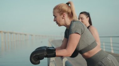 İki kadın, deniz kenarında boks sonrası antrenman yaparken, spor yaparken, spor yaparken ve arkadaşlık yaparken ödüllendirici bir anı paylaşıyor..