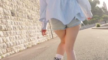 Güneşli bir günde dışarıda paten kaymaktan hoşlanan tanınmayan genç bir kadın özgürlük ve neşe hissi yaratıyor..