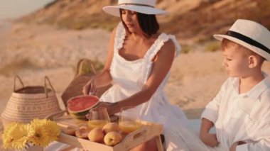 Anne ve oğlu sahilde rahatlatıcı bir pikniğin tadını çıkarıyorlar. Bu iç açıcı sahne yazın, ailenin ve kaliteli zamanın özünü yakalar..