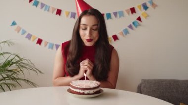 Güzel bir kadın doğum günü solosunu kutlarken düşünceli bir an. Kutlama süslemelerinin ortasında pastasının üzerine mum üflerken..