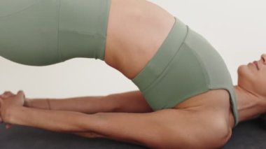 Yoga yapan bir kadını yakalamak için detaylı bir yakın plan çekimi, sakinlik yaymak ve evde spor yaparken odaklanmak..
