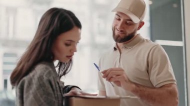 Profesyonel bir kurye servis sahnesi. Teslimatçı imzası için bir paketi müşteriye teslim ediyor. Hizmet kalitesini sembolize ediyor.