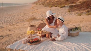 Sevgi dolu bir anne ve küçük oğlu güneşli bir sahilde keyifli bir pikniğin tadını çıkarıyorlar. Gülüşleri, kahkahaları ve lezzetli yemekleri paylaşıyorlar. Birlikte değerli anılar yaratıyorlar..