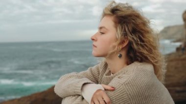 Denizin kenarında meditasyon yapan bir kadınla sakin bir sahne. Uçurumun kenarındaki huzurlu okyanus ritmini hissediyor..