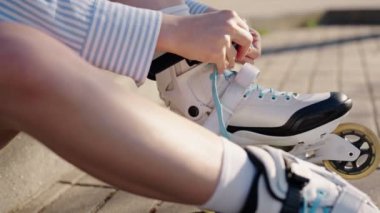 Kimliği belirsiz genç bir kadın güneşli bir günde patenlerini dışarıda bağlayıp paten kaymaya hazırlanıyor. Sağlıklı yaşam tarzı ve eğlence kavramı.