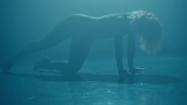 Zarif genç bayan loş ışıklı stüdyoda dans ederek dans hareketini ve duygusunu yakalıyor..