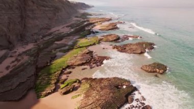 Okyanus dalgalarının arka planda güzel kayalıklar olan kayalık bir plaja düşüşünü gösteren hava manzarası. Seyahat, doğa ve rahatlama videoları için mükemmel..