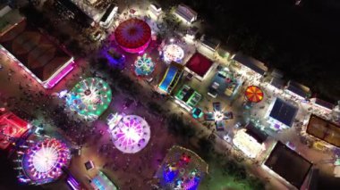 Renkli ışıkların, gezintilerin ve gece eğlencelerinin olduğu bir karnaval. Eğlence parkının kuş bakışı görüntüsü.
