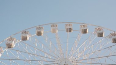 Panayırda ya da lunaparkta mavi gökyüzüne karşı dönen beyaz dönme dolabın zamanlaması.