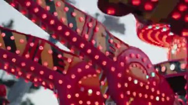 Kırmızı ve yeşil ışıkları yanıp sönen bir panayırda dönen bir lunaparka yakın çekim. Eğlence parkları, karnavallar, devlet fuarları, eğlence, eğlence ve çocukluk projeleri için mükemmel..