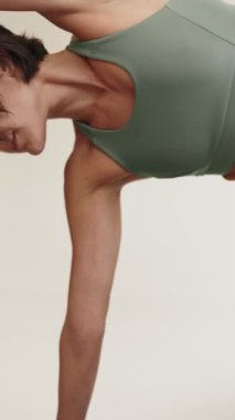 Yoga yapan bir kadının detaylarını yakına çekerek, kaslı vücudunu ve uygunluk ve esneklik kavramını vurgulayarak..