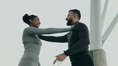 Çok kültürlü bir çift, bir fitness rutinine girişir, kent zeminine karşı odak ve kararlılıkla birlikte gerilir.