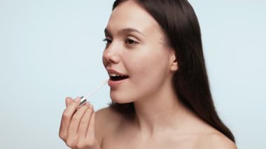 Dudaklarına nazikçe dudak kremi süren genç bir dişi dudak bakımı ve hijyen için günlük güzellik rutini..